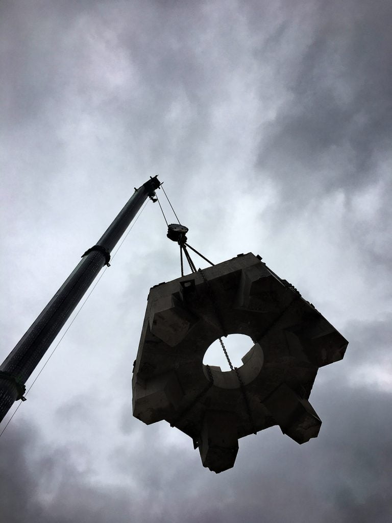 A silhouette of section of the Coventry Cross Monument being lifted